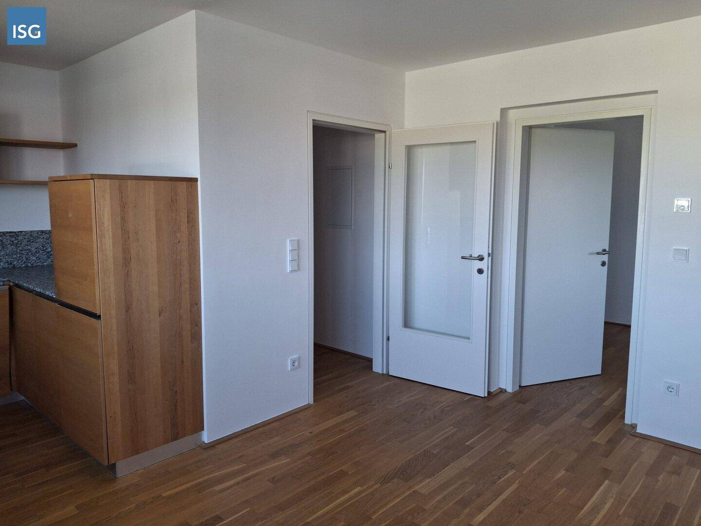 Heller Flur mit Parkettboden und mehreren Türen, angrenzend an einen Küchenbereich.