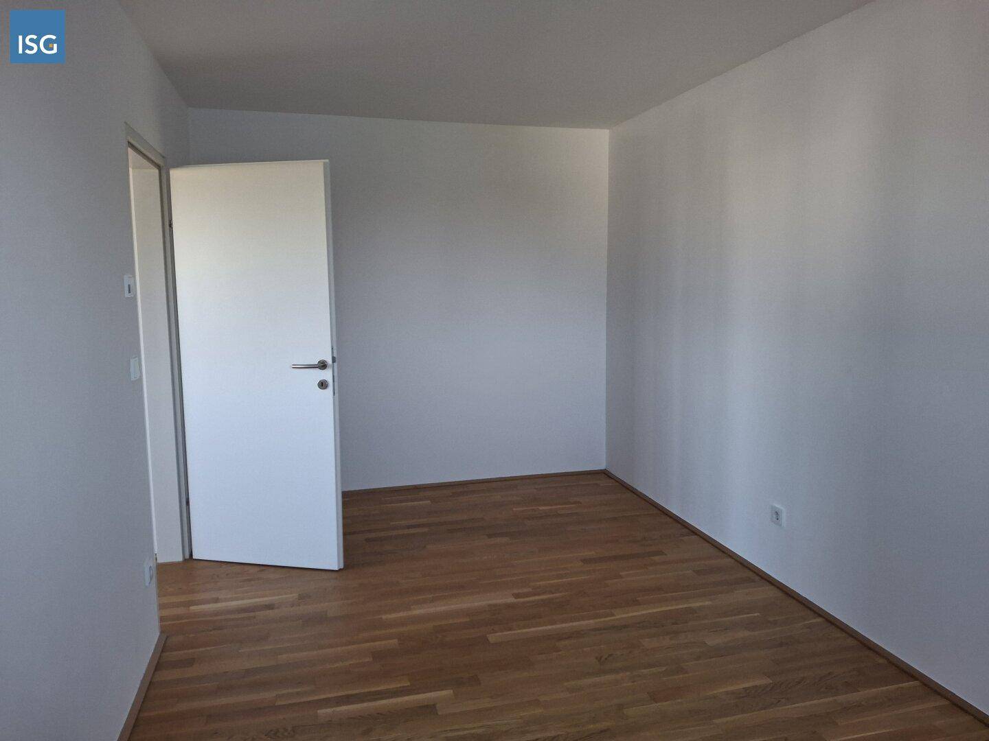 Leeres Zimmer mit hellem Parkettboden und weiß gestrichenen Wänden, bereit zum Einzug.