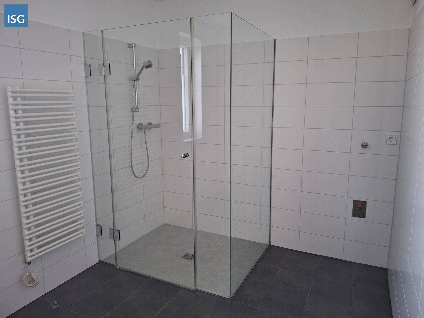 Modernes Badezimmer mit großer Glasdusche, weißen Fliesen und Handtuchheizkörper.