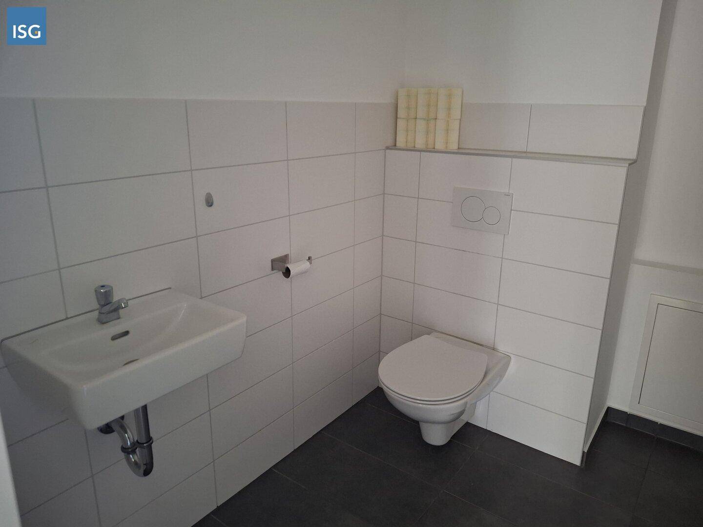 Separates Gäste-WC mit wandhängender Toilette und kleinem Waschbecken.