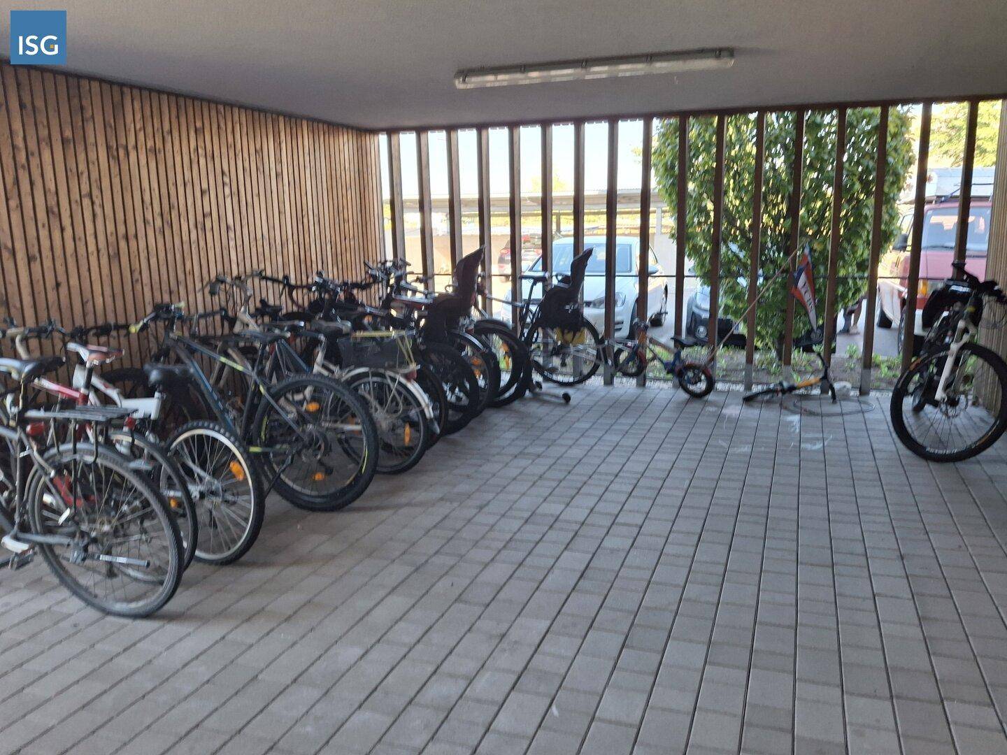Überdachter Fahrradabstellplatz mit zahlreichen Fahrrädern und Holzlamellenverkleidung.