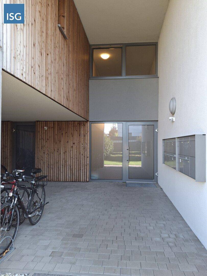 Moderner Eingangsbereich eines Gebäudes mit Holzverkleidung und Fahrradabstellmöglichkeiten.