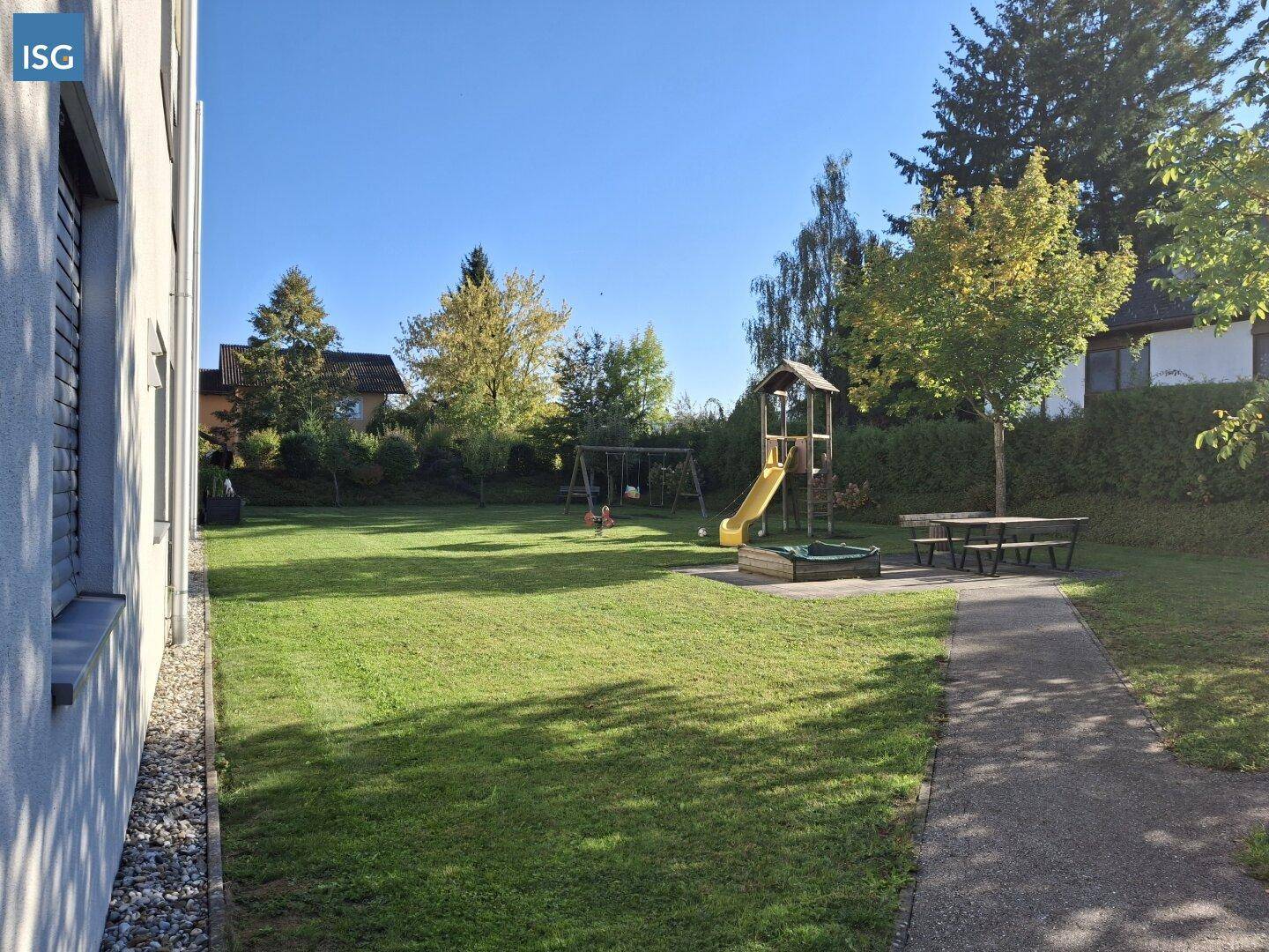 Weitläufiger Gemeinschaftsgarten mit Spielgeräten, Sandkasten und Sitzgelegenheiten.