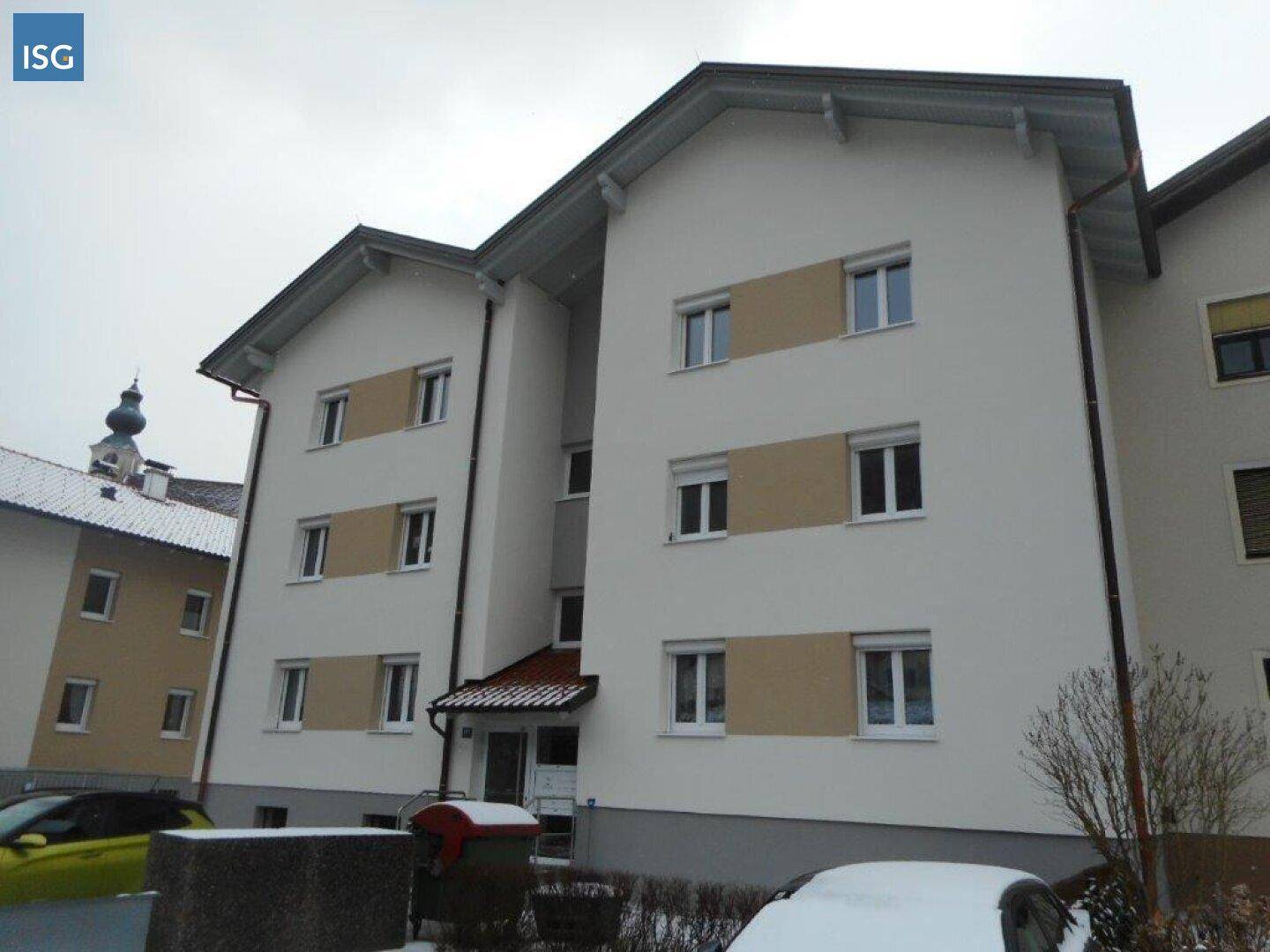 Ansicht der Gebäudefassade mit Fenstern, Rollläden und einem Satteldach, umgeben von Schnee.