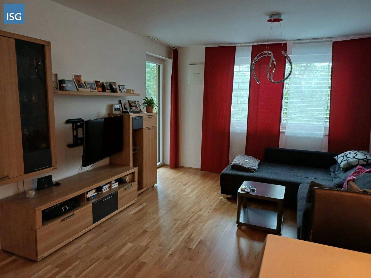 Gemütliches Wohnzimmer mit Holzboden, Sofa und Zugang zu einem Außenbereich.