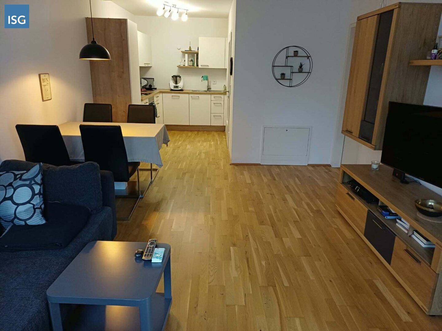 Offener Wohn-Essbereich mit integrierter Küche, Holzboden und moderner Einrichtung.