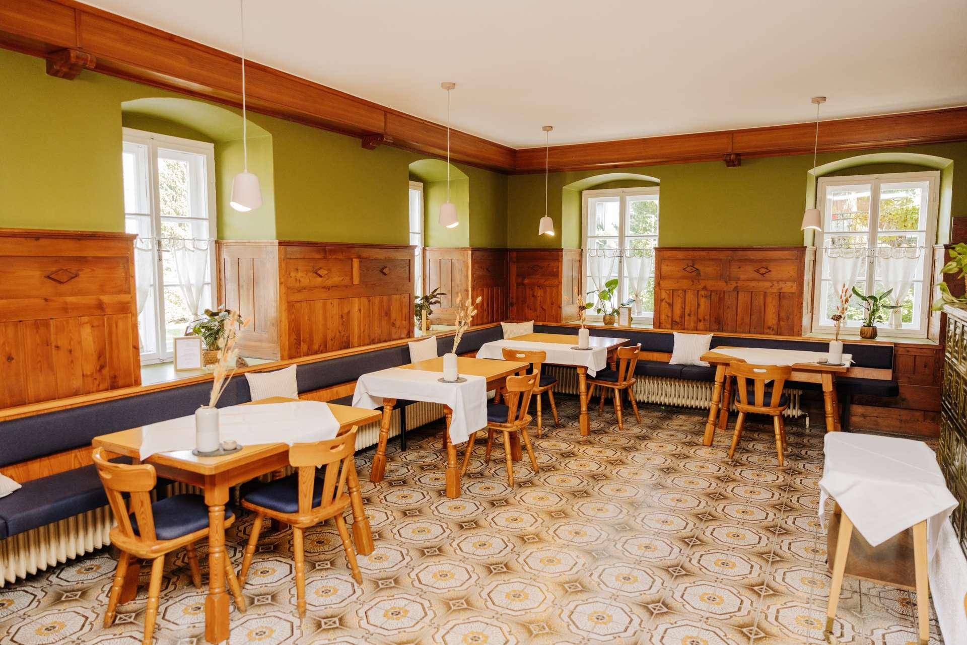 Traditioneller Speisesaal mit Holztäfelung, gemustertem Fliesenboden und mehreren Tischen für Gäste.