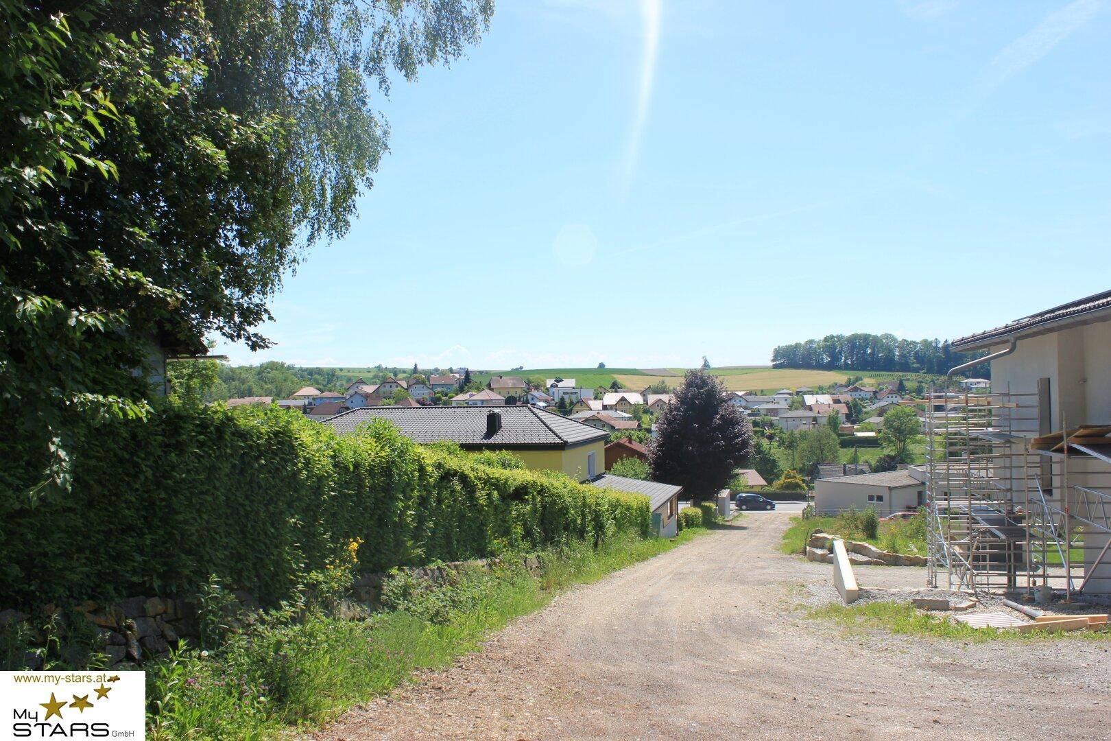 Panoramablick über eine ländliche Siedlung mit weiten Feldern und einem sonnigen Himmel.