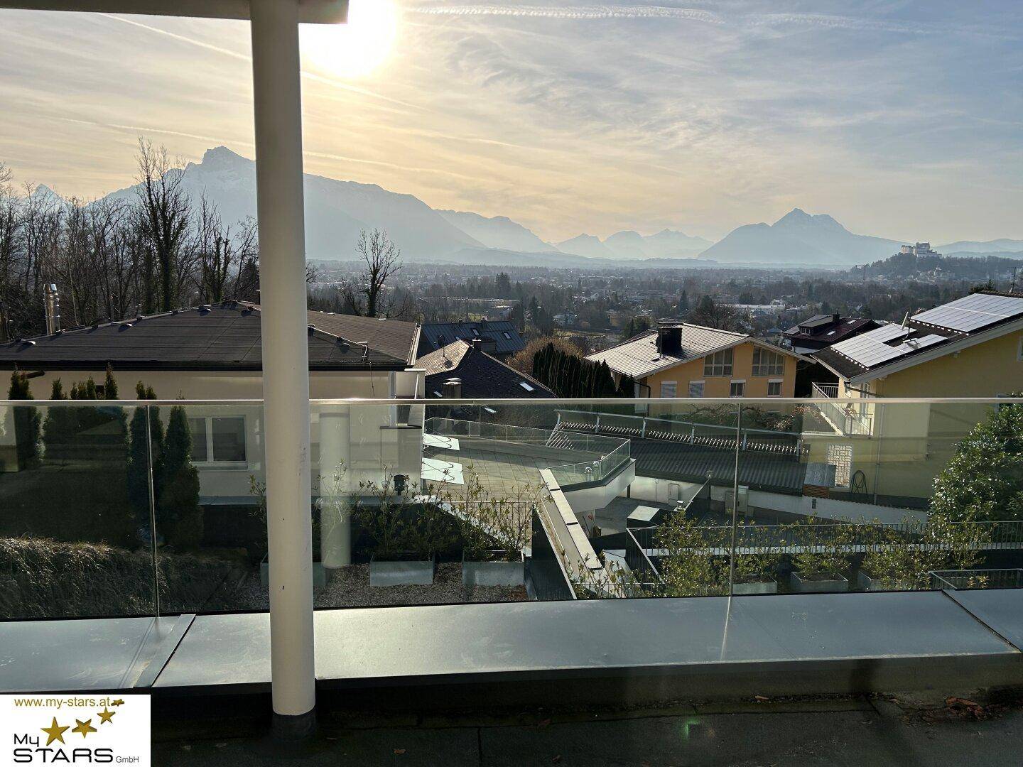 Weitläufiger Blick über die Stadt und die umliegende Berglandschaft bei Sonnenuntergang.