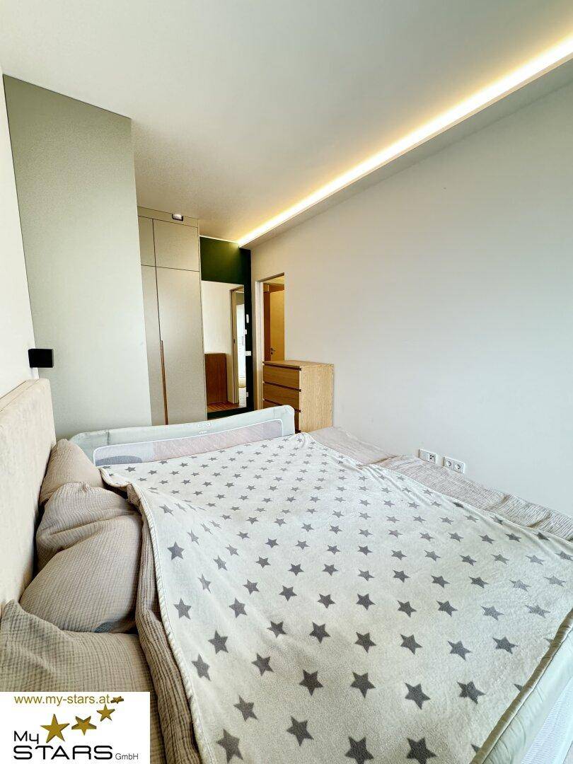 Schlafzimmer mit großem Bett, indirekter Beleuchtung und modernem Design.