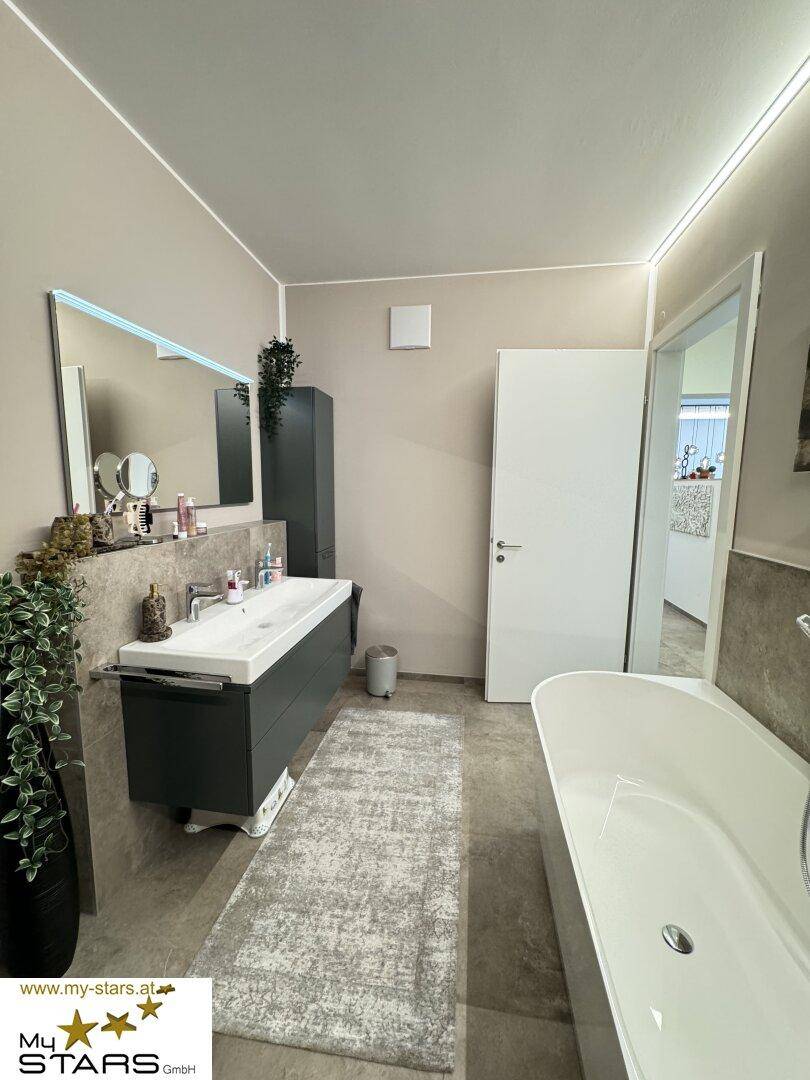 Geräumiges Badezimmer mit freistehender Badewanne und modernem Doppelwaschbecken.