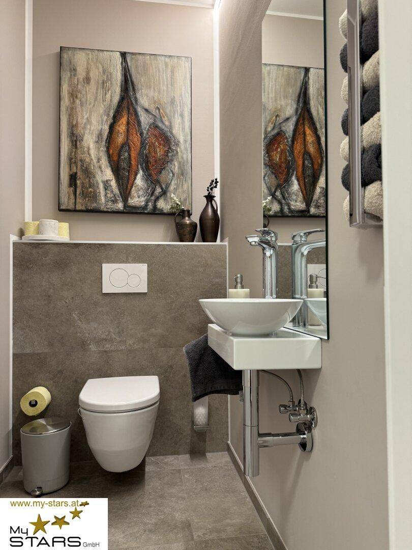 Modernes Gäste-WC mit Wand-WC, kleinem Waschbecken und stilvoller Wandkunst.