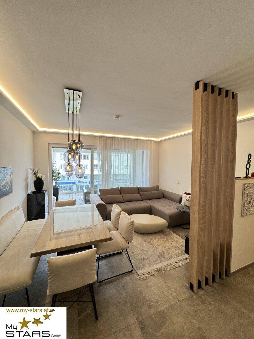 Offener Wohn-Essbereich mit großem Sofa, Esstisch und moderner Beleuchtung.