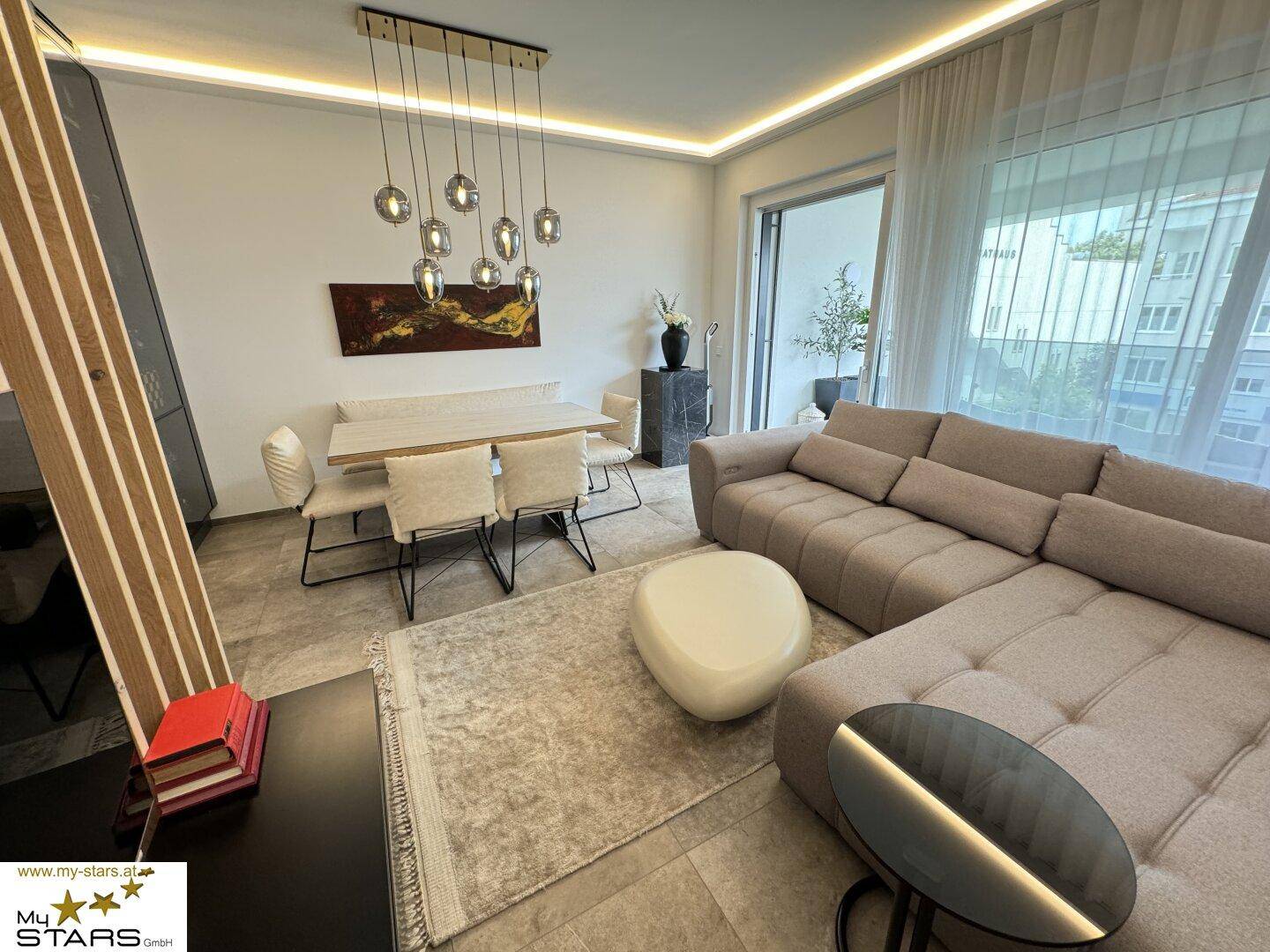 Heller Wohn-Essbereich mit beigem Sofa, Esstisch und Zugang zum Balkon.
