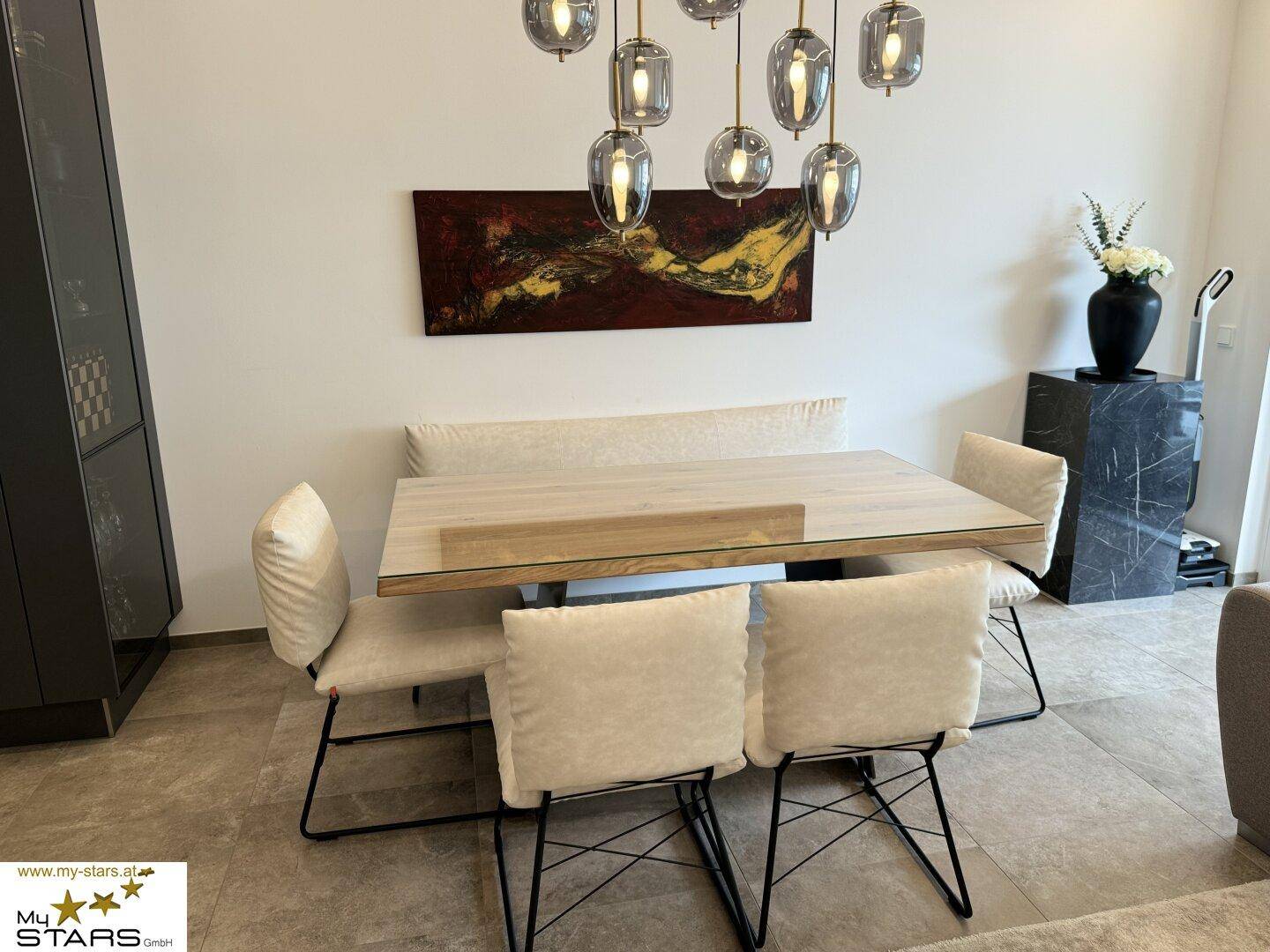 Eleganter Essbereich mit Holztisch, gepolsterten Stühlen und dekorativer Beleuchtung.