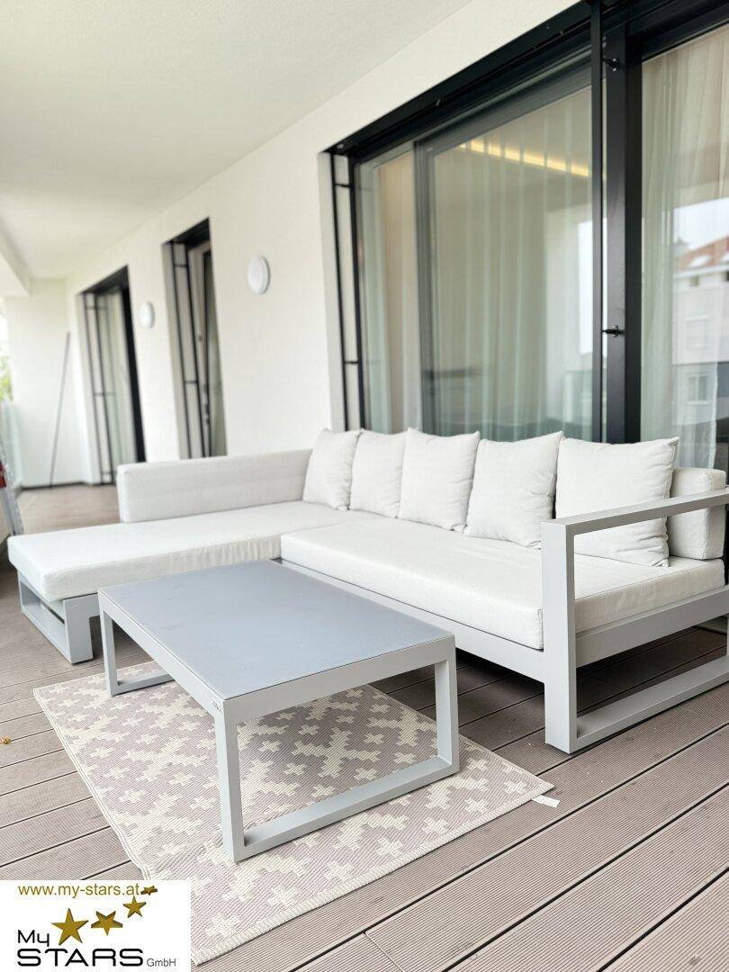 Geräumiger Balkon mit bequemen Outdoor-Möbeln und Blick auf die Umgebung.
