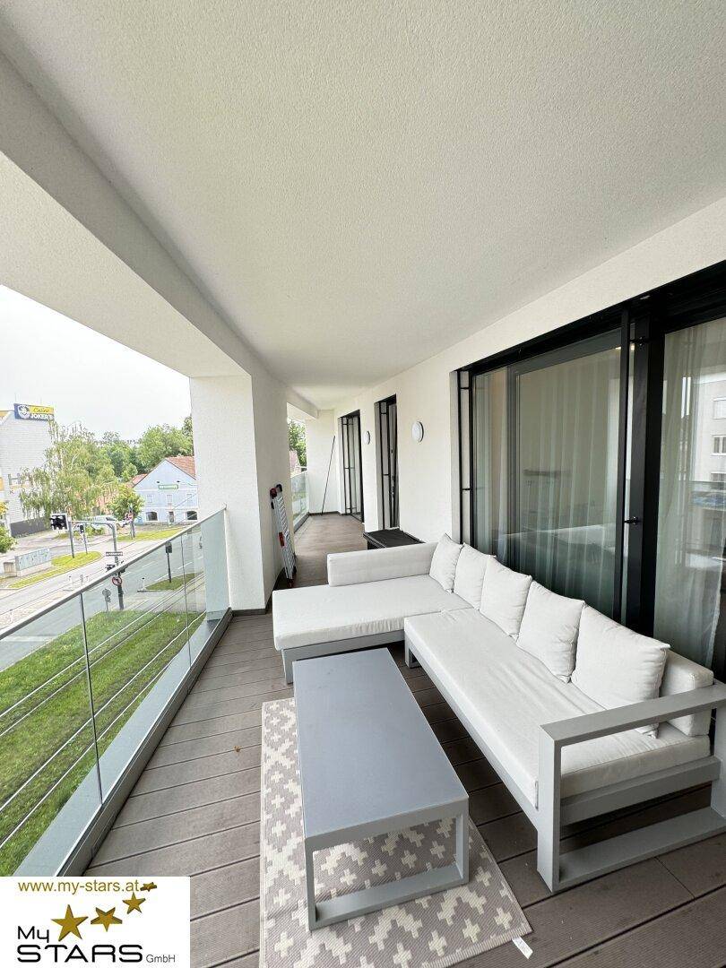 Geräumiger Balkon mit modernen Outdoor-Möbeln und Blick auf die Stadt.