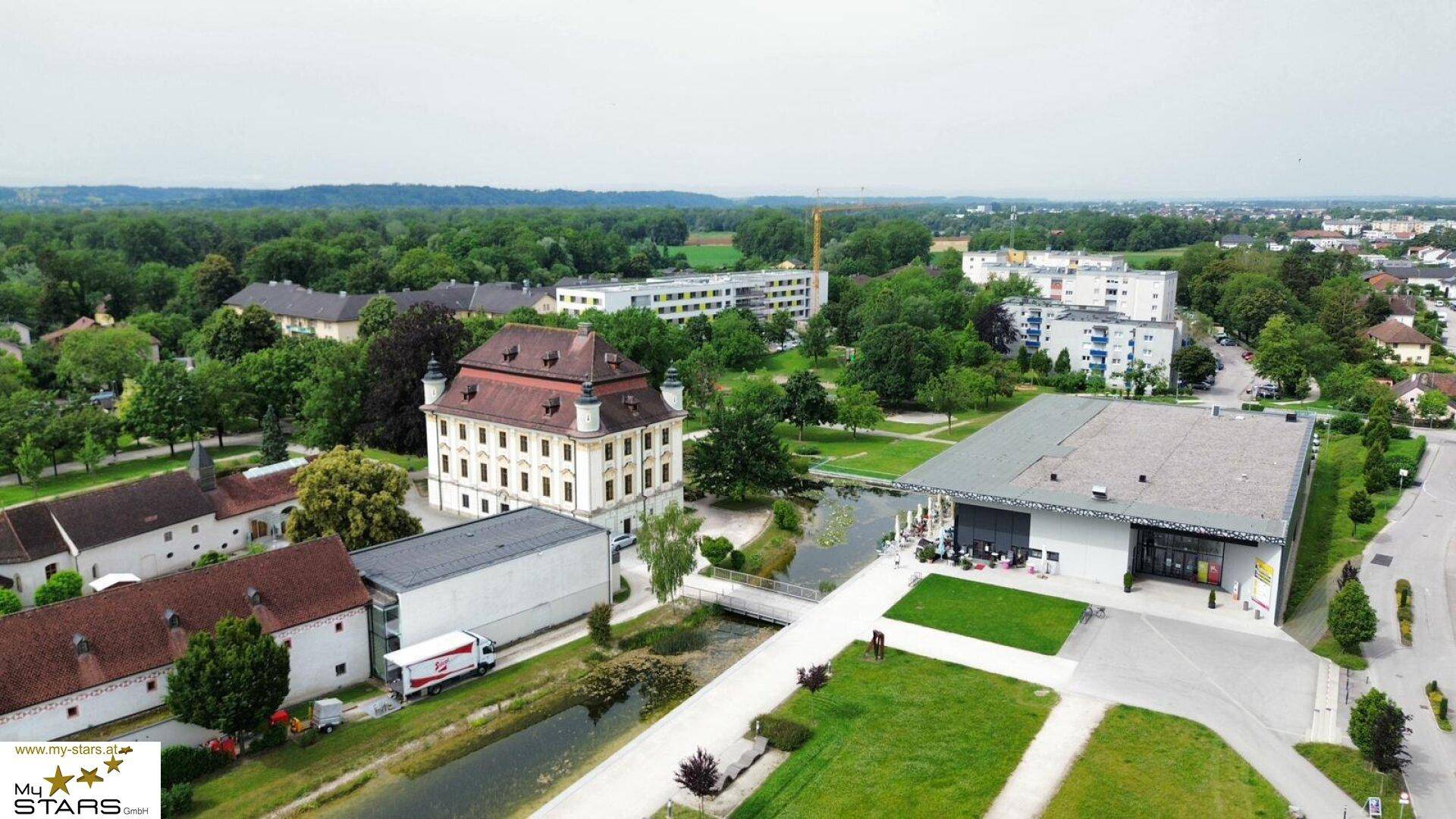 Weitläufige Luftaufnahme eines historischen Anwesens mit Park und Wasserflächen.