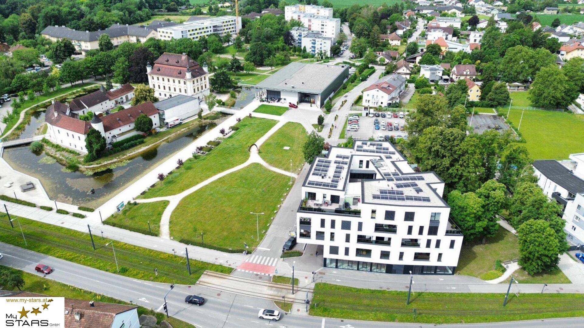 Luftaufnahme einer modernen Wohnanlage mit Solarpaneelen, die sich harmonisch in die städtische Umgebung mit historischen Gebäuden einfügt.