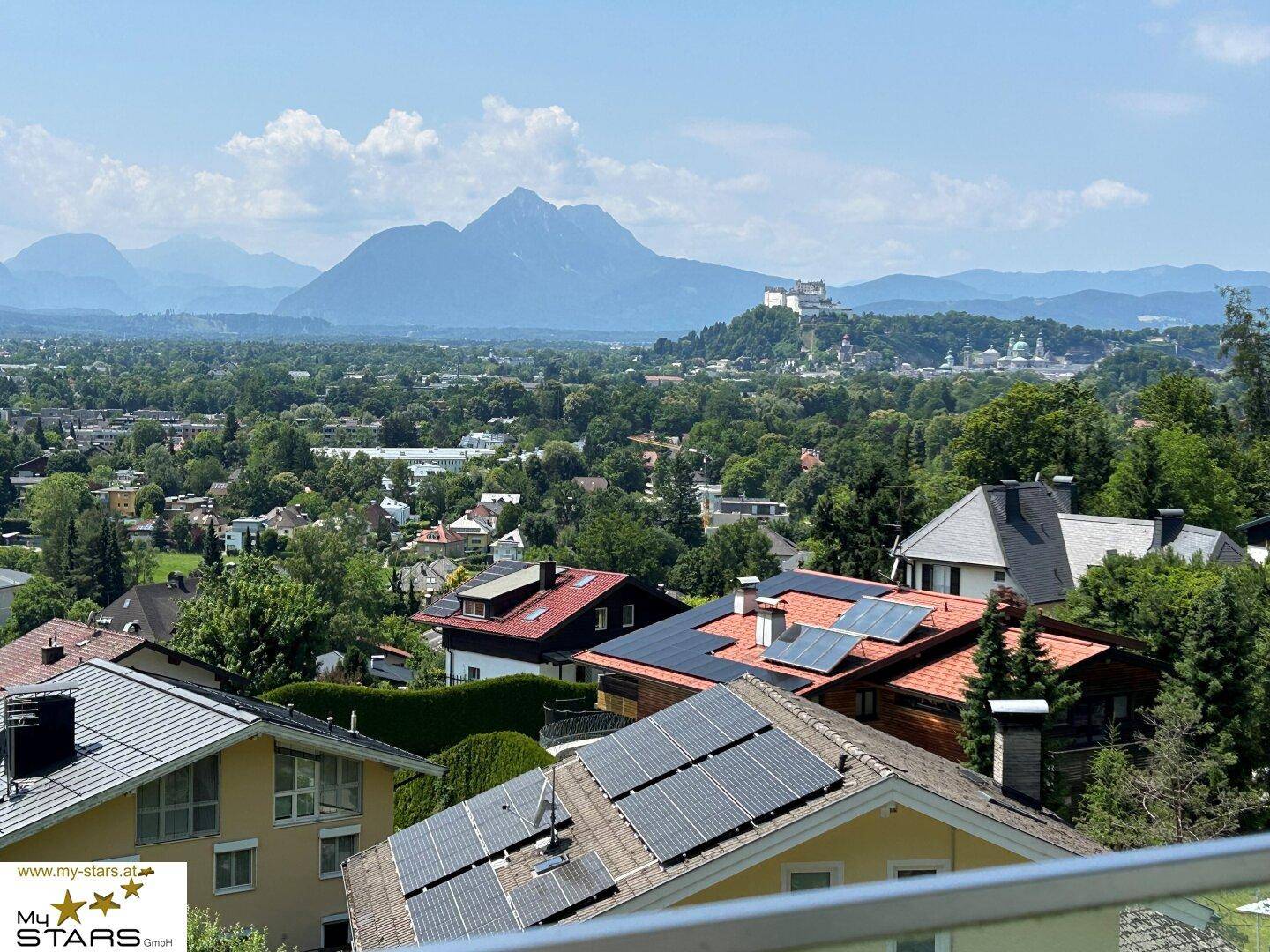 Panoramablick über die Stadt Salzburg mit Bergen und Festung Hohensalzburg im Hintergrund.