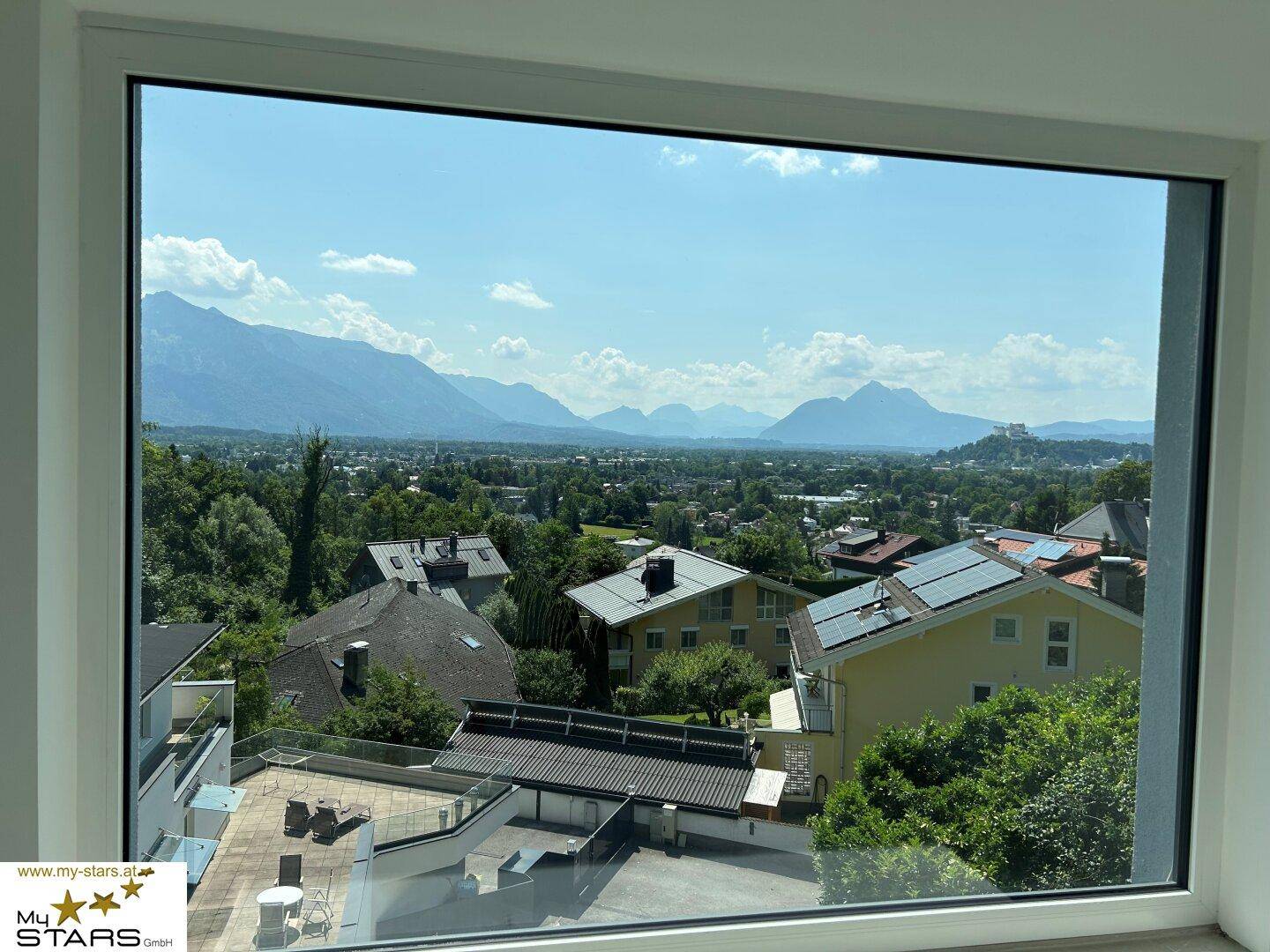 Großes Fenster mit weitem Blick über die Stadt und die umliegende Berglandschaft.