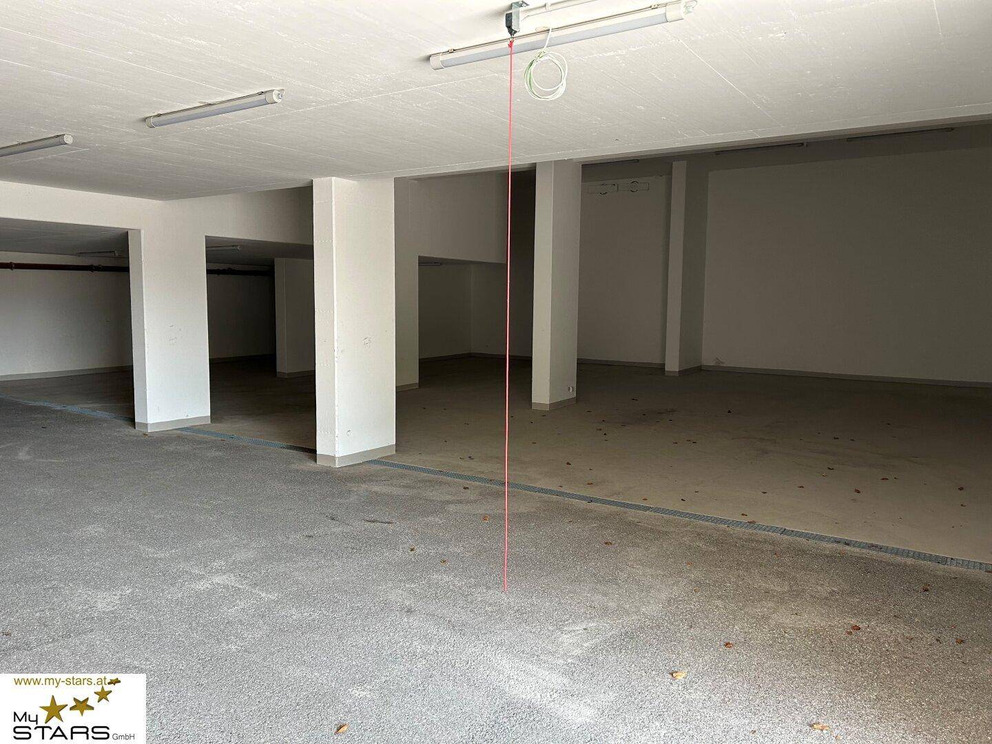 Geräumige Tiefgarage oder Kellerfläche mit Betonboden und Säulen.