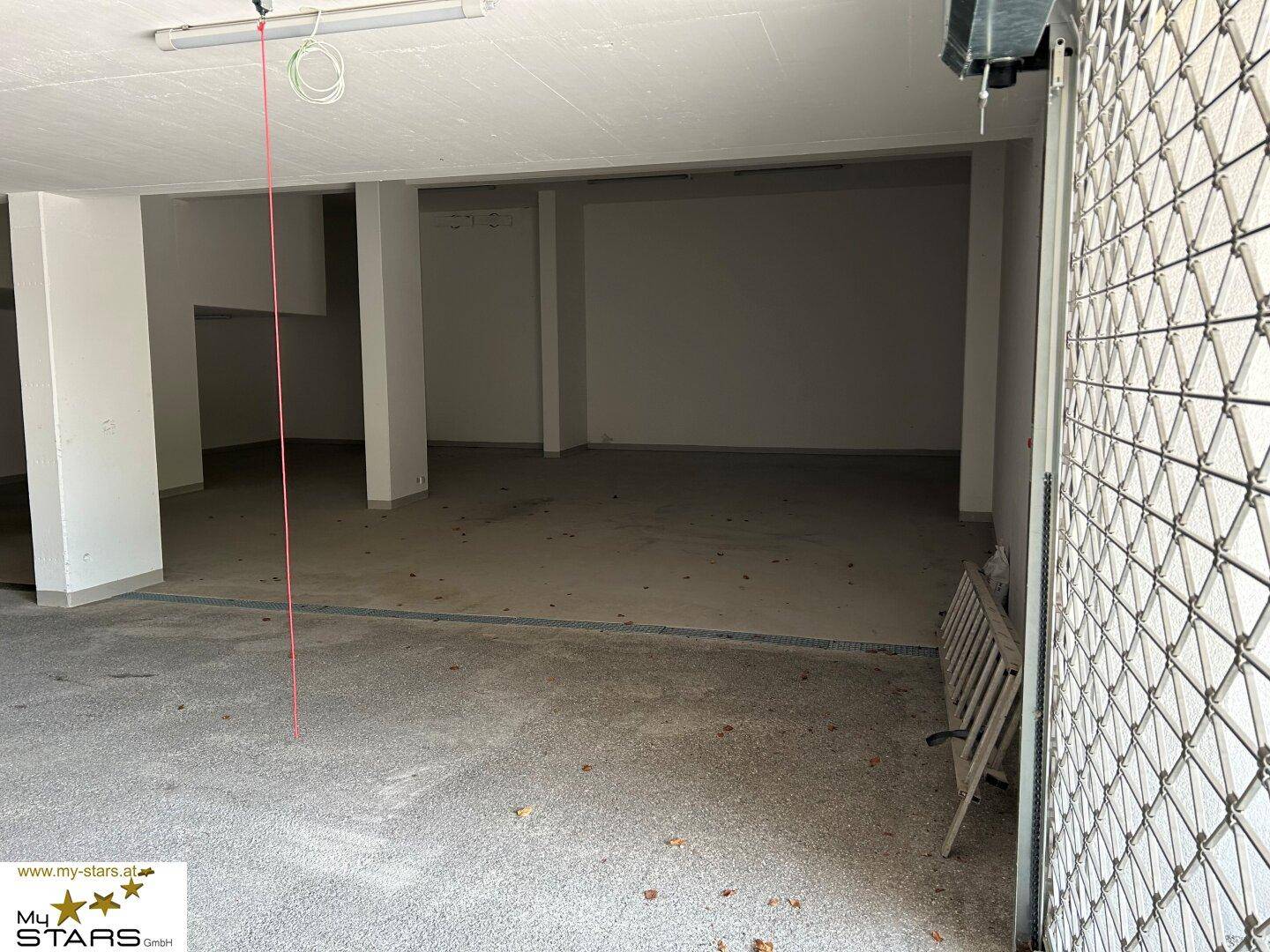 Großer, leerer Garagenraum mit Rolltor und Betonboden.