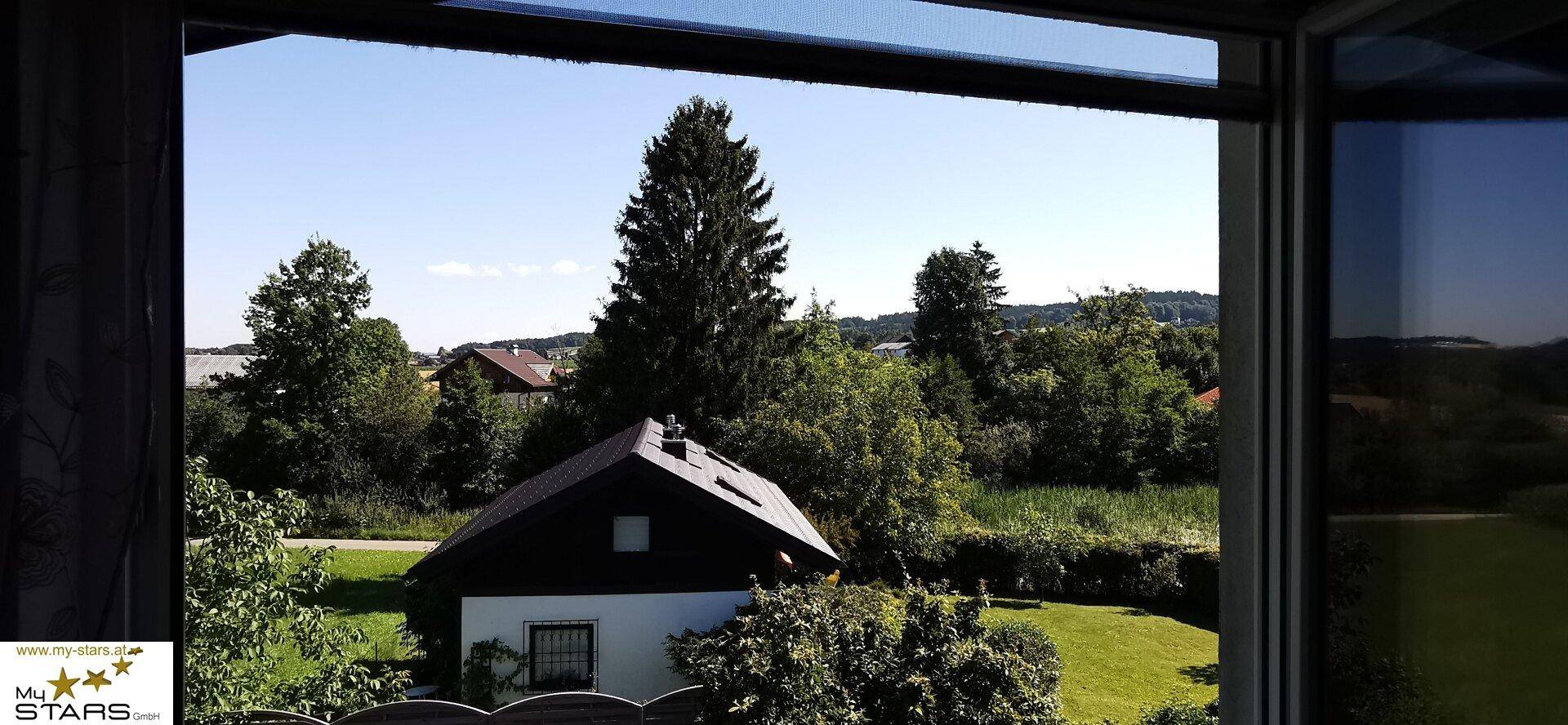 Weitläufiger Blick aus dem Fenster auf grüne Landschaft und ein weiteres Haus.