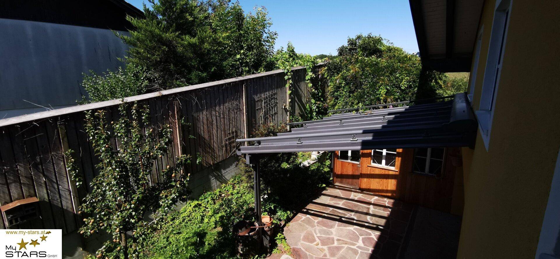 Überdachter Terrassenbereich mit Glasdach und Holzwänden, von oben betrachtet.