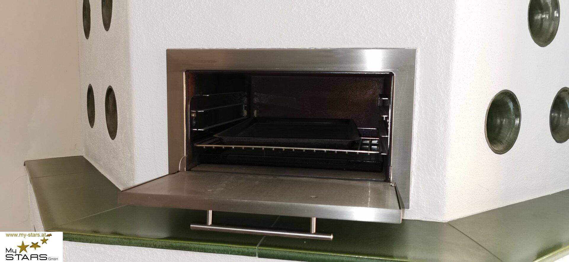 Integrierter Backofen in einem traditionellen Kachelofen mit Metallfront.