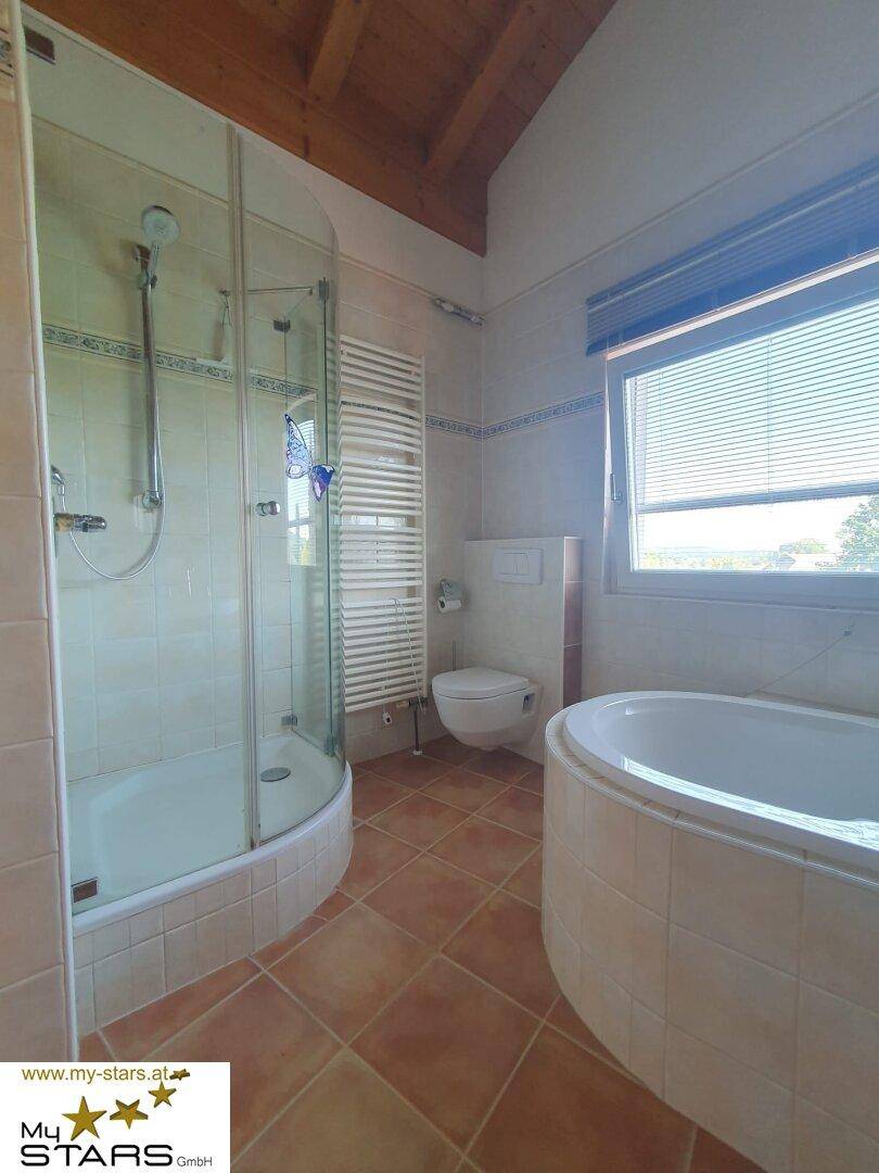 Badezimmer mit Duschkabine, Badewanne, Toilette und beheiztem Handtuchhalter.
