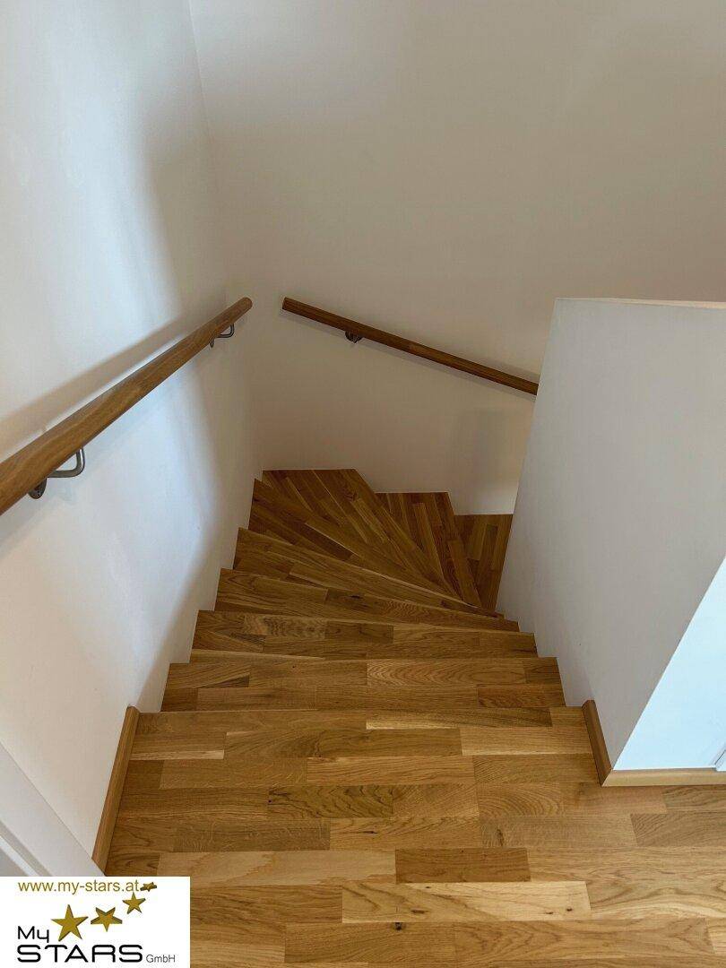 Elegante Holztreppe mit Geländer, die die verschiedenen Etagen des Hauses verbindet.