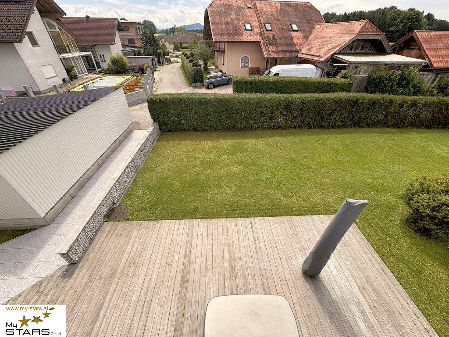 Große Holzterrasse mit Blick auf den Garten und die umliegende Wohngegend.