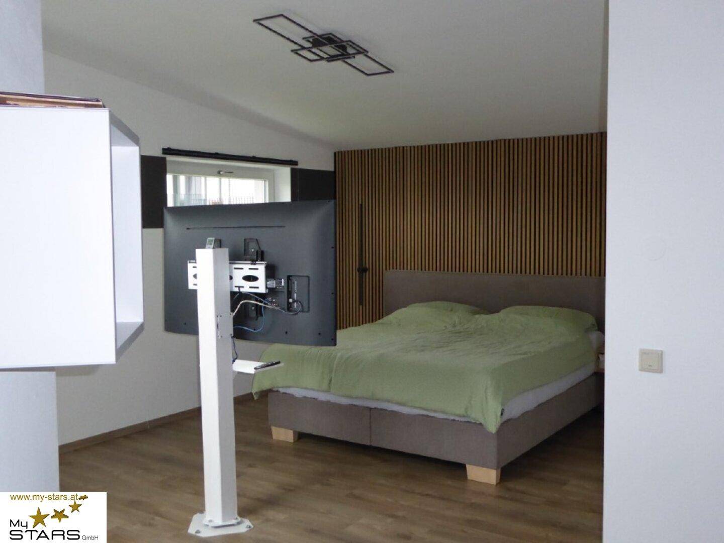 Schlafzimmer mit modernem Design, Holzwand und großem Bett.