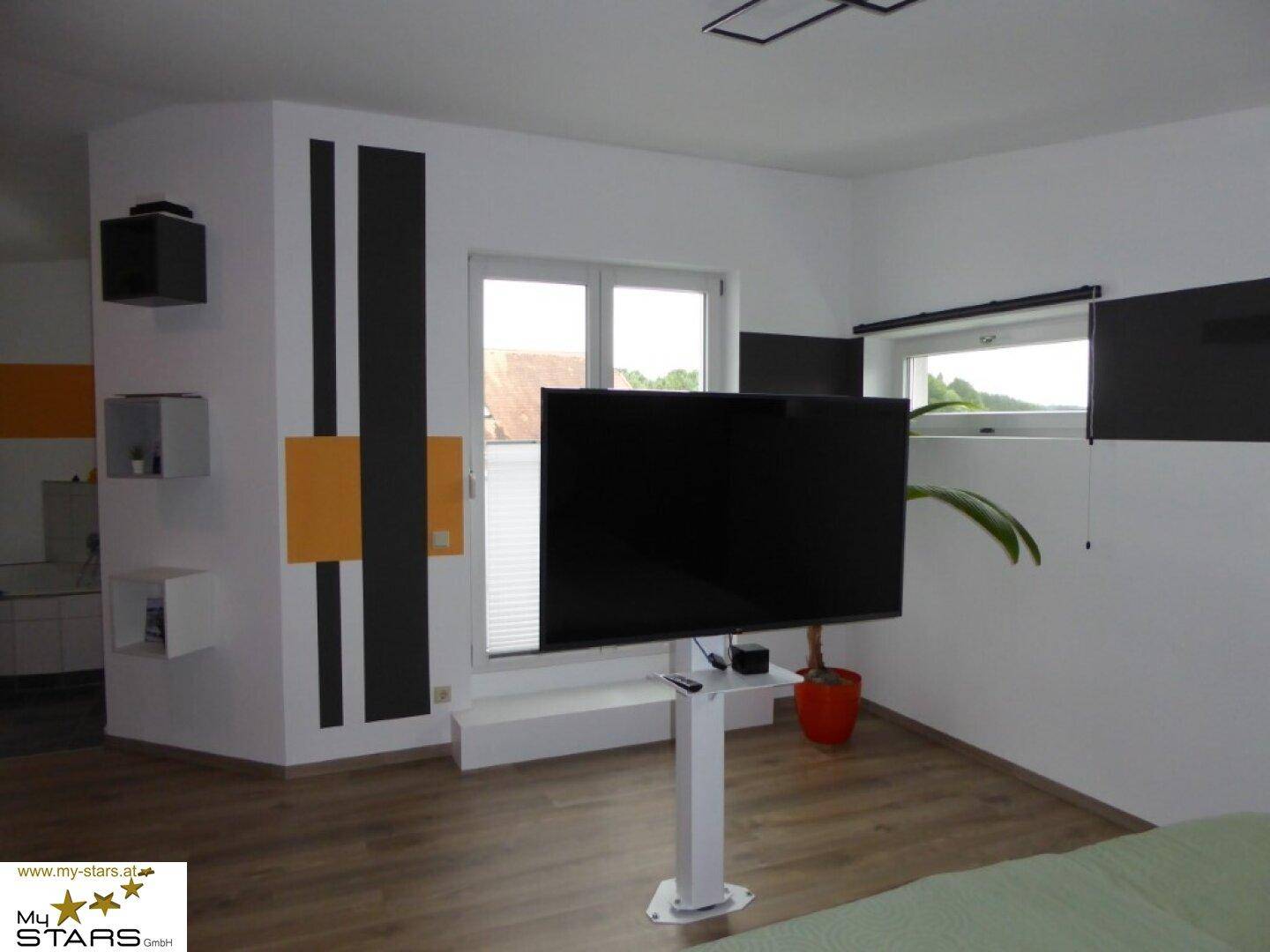 Helles Schlafzimmer mit modernen Akzenten, Fenster und Zugang zum Balkon.
