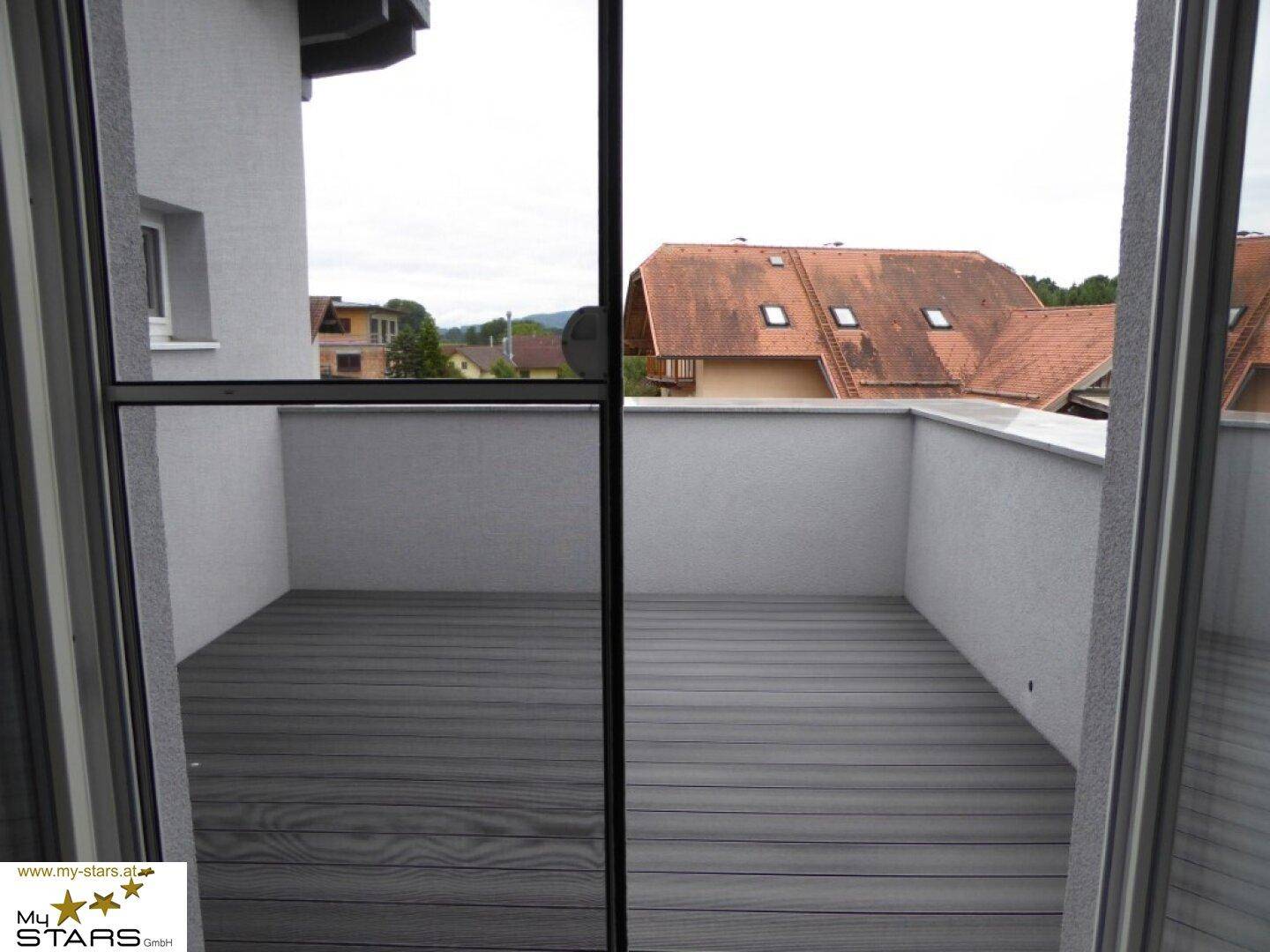 Geräumiger Balkon mit Holzboden und Blick auf die Nachbarschaft.