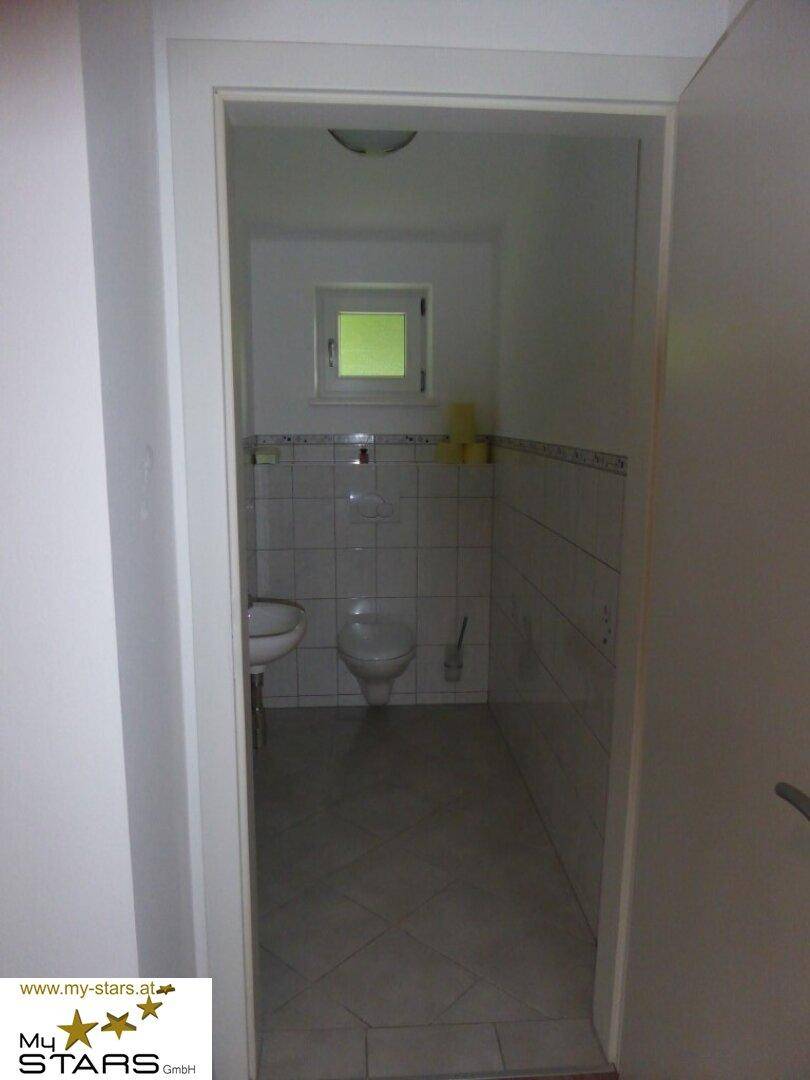 Kleines Gäste-WC mit Fenster, Toilette und Waschbecken.
