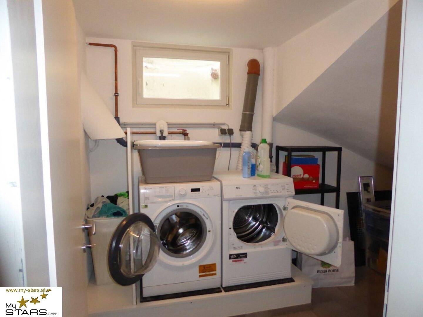 Hauswirtschaftsraum mit Waschmaschine, Trockner und Fenster.