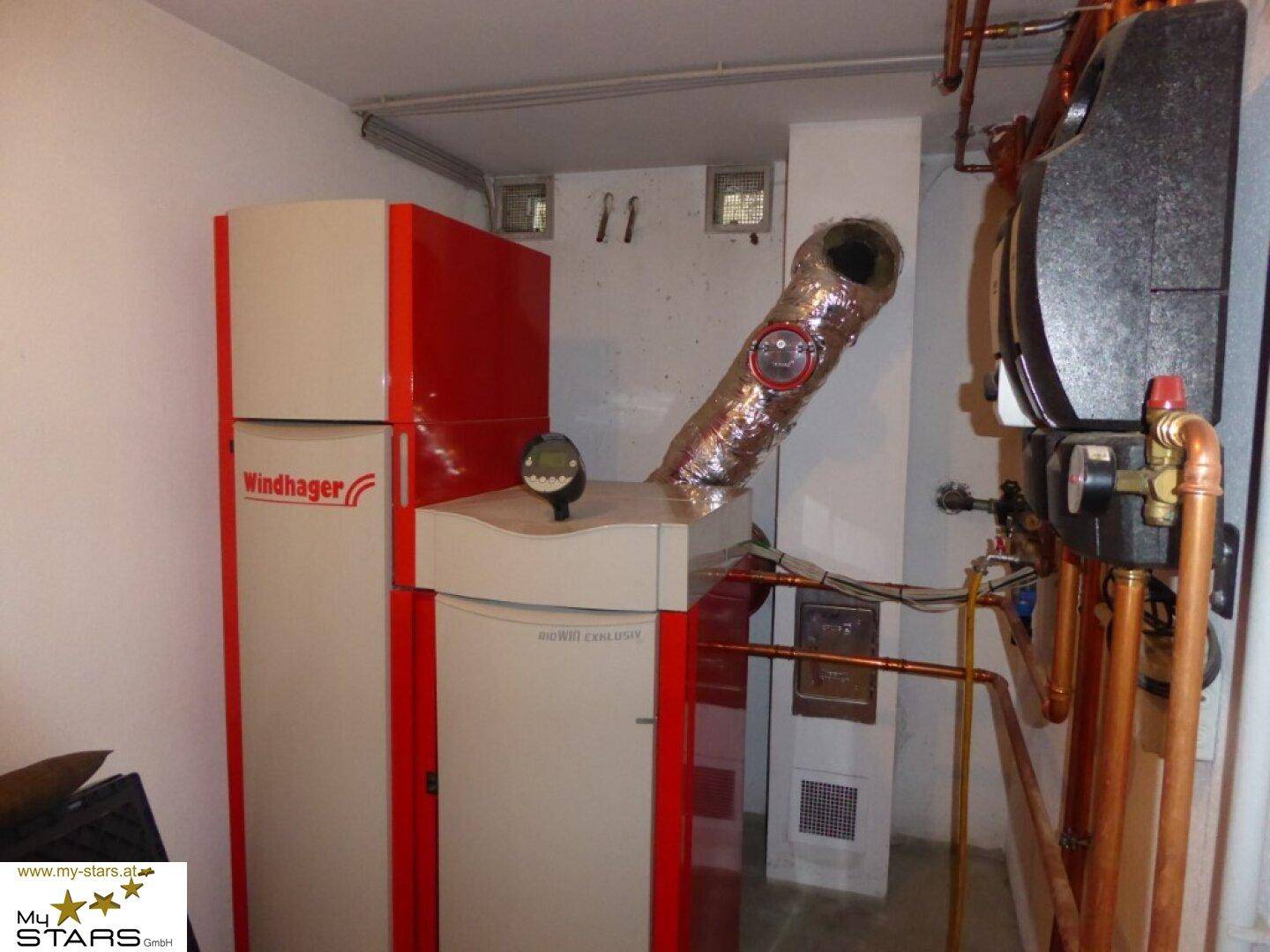 Heizungsraum mit moderner Windhager Pelletheizung und Warmwasserspeicher.