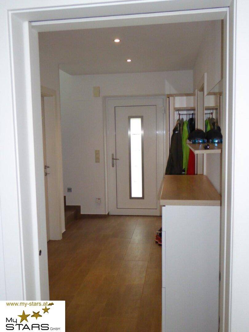 Heller Eingangsbereich mit Garderobe, Schuhschrank und Holzboden.