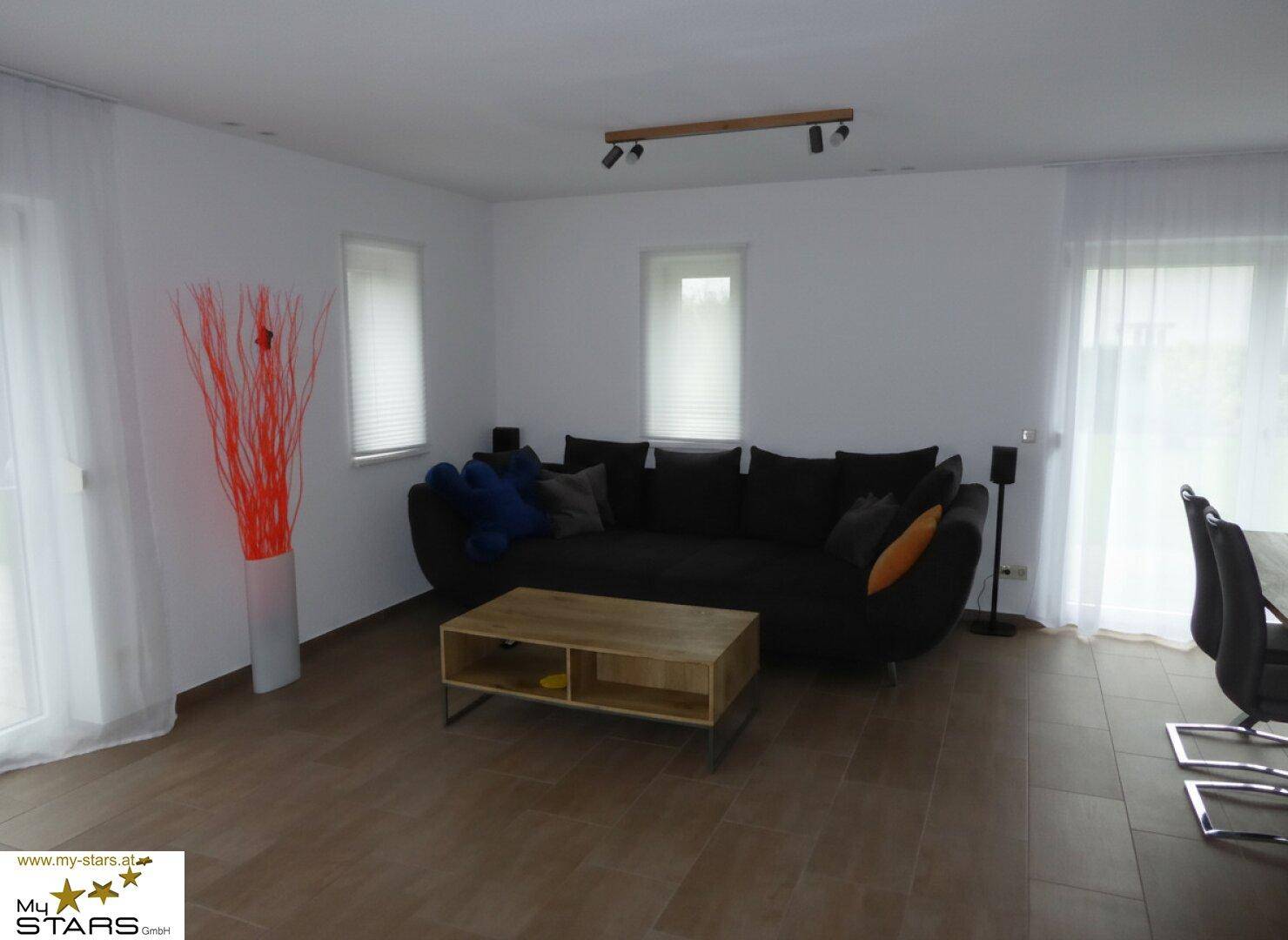 Helles Wohnzimmer mit großem Sofa, Couchtisch und Zugang zur Terrasse.