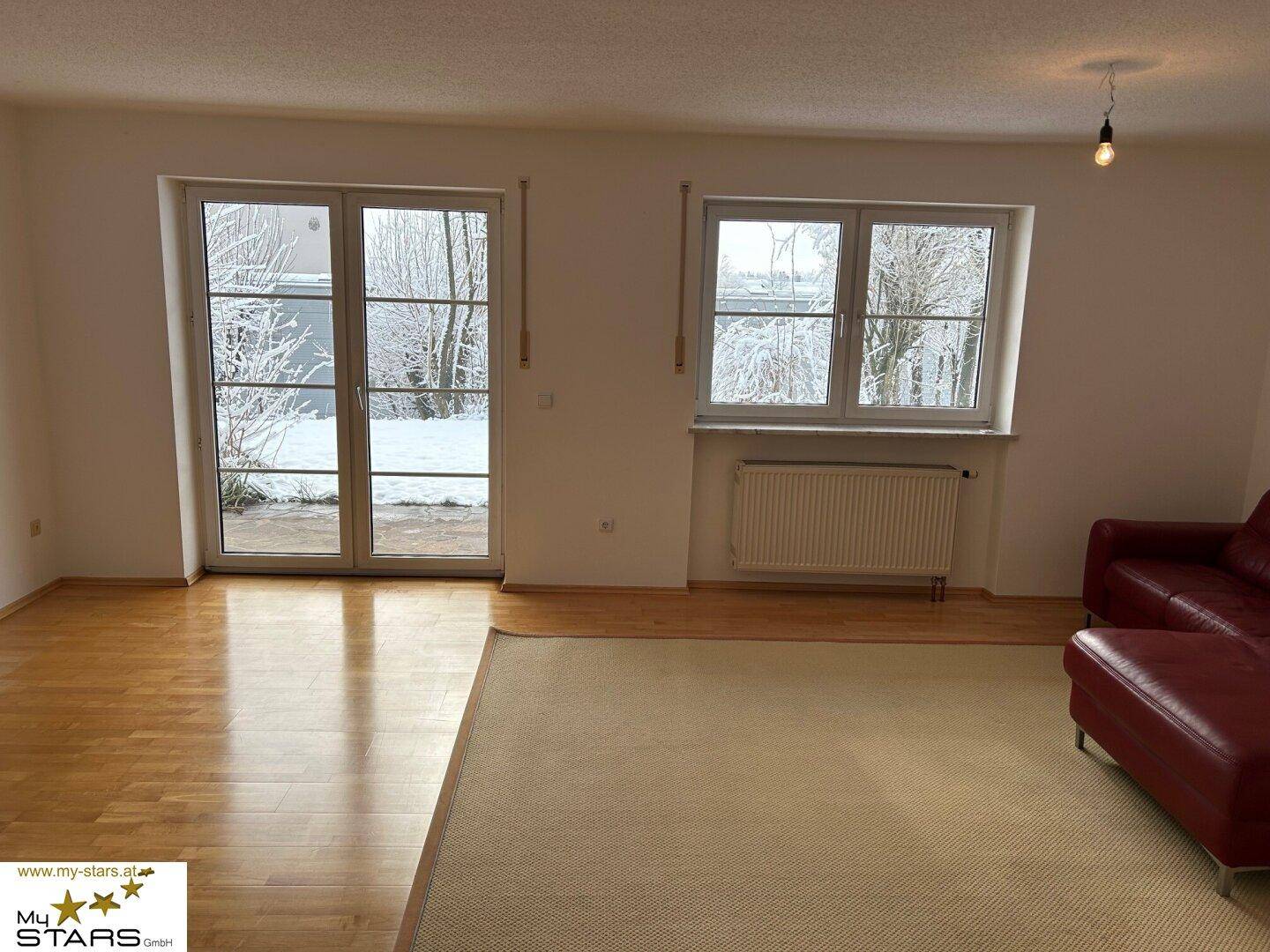 Geräumiges Wohnzimmer mit Parkettboden, Zugang zur Terrasse und Blick in den Garten.