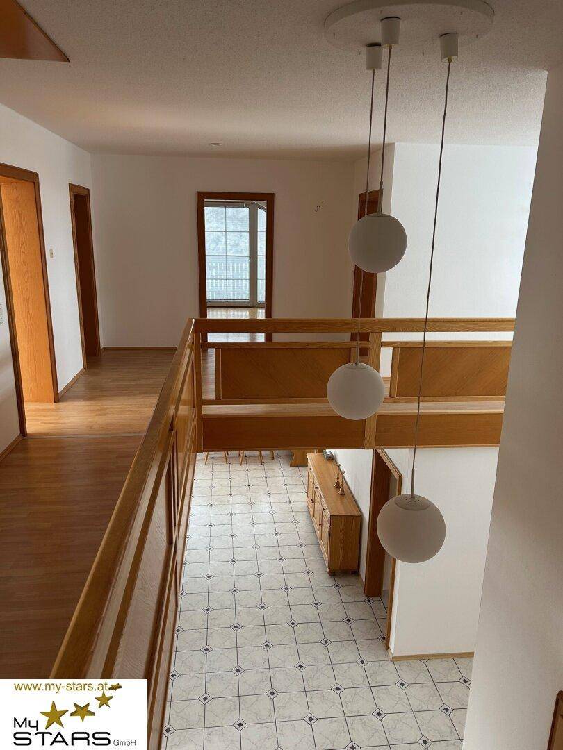 Heller Flur mit Holzgeländer, Fliesenboden und Blick auf die untere Etage.