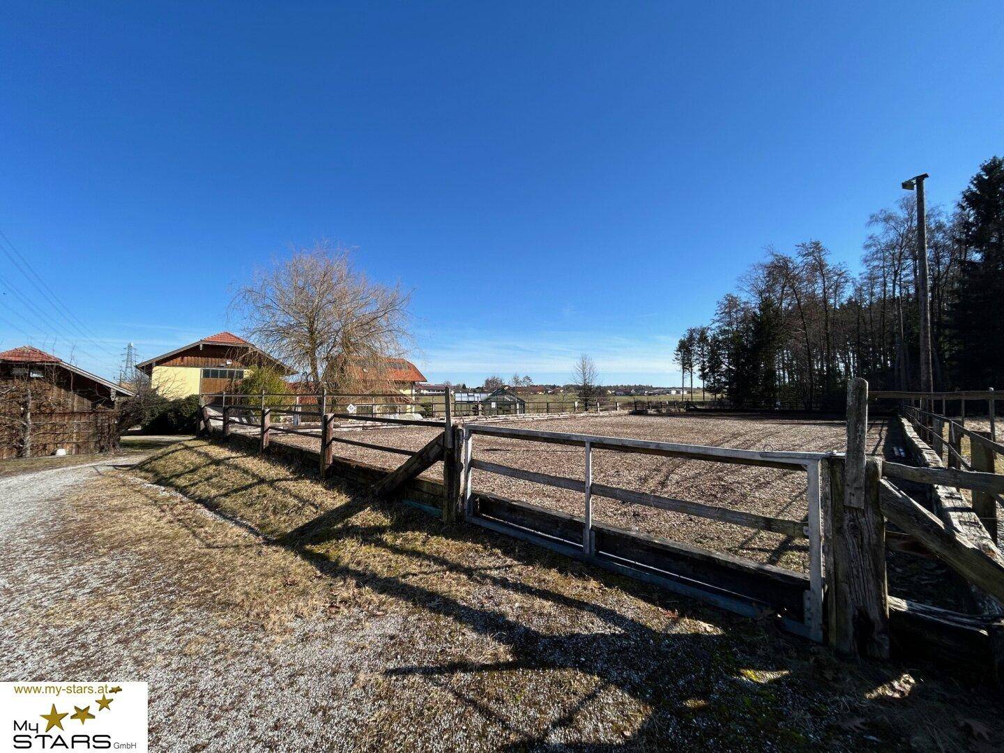 Weitläufiger, eingezäunter Außenbereich mit Blick auf die ländliche Umgebung und weitere Gebäude.