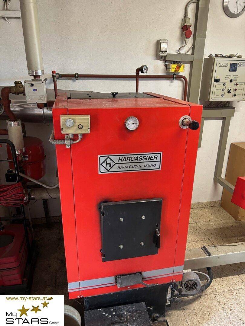 Rote Hackgut-Heizungsanlage in einem Technikraum, sorgt für effiziente Wärmeversorgung des Anwesens.