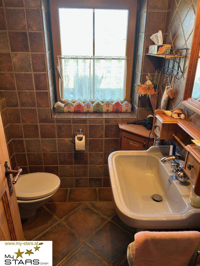 Kleines Gäste-WC mit Terrakotta-Fliesen, Fenster und traditionellem Waschbecken.