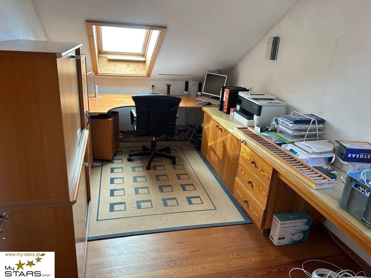 Helles Dachgeschoss-Büro mit Holzmöbeln, Schreibtisch und Dachfenster, ideal zum Arbeiten.