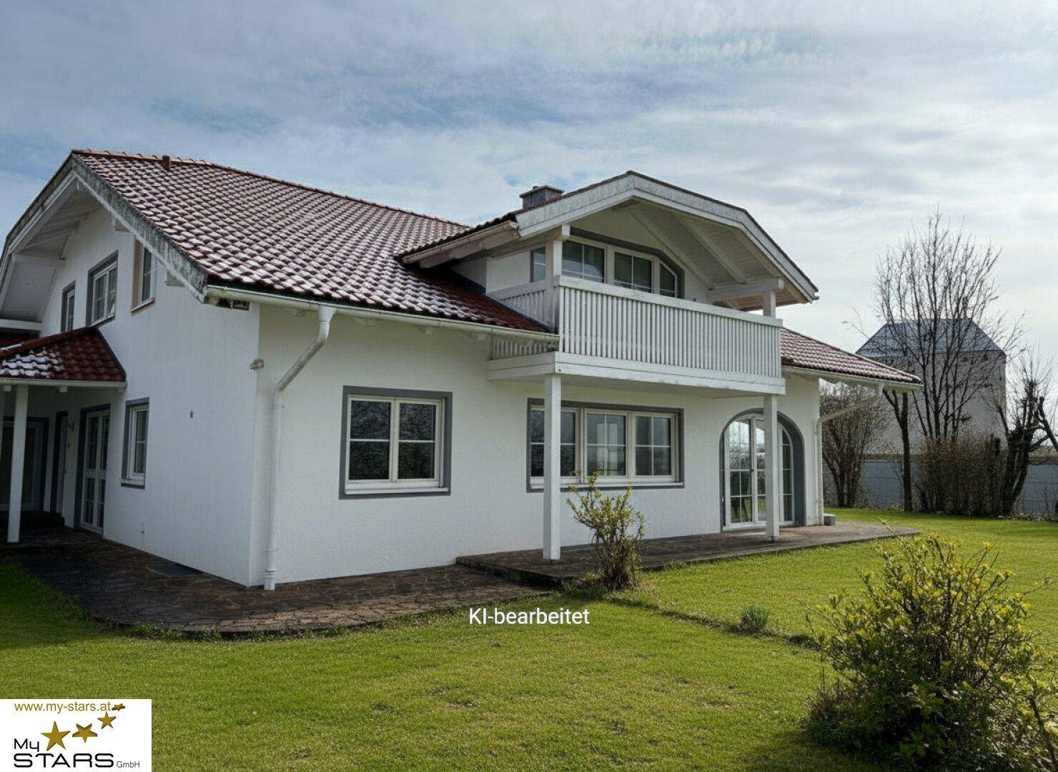 Modernes Einfamilienhaus mit weißer Fassade, rotem Satteldach und Balkon, umgeben von einem gepflegten Rasen.
