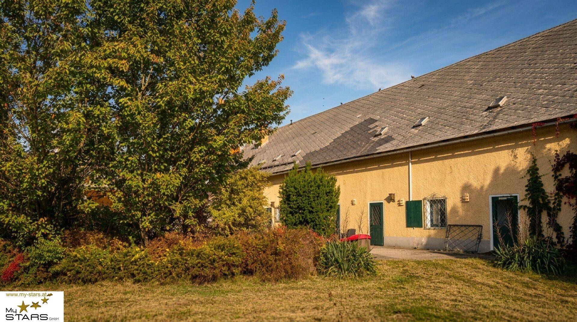 Seitenansicht des Gebäudes mit üppiger Vegetation und einem gepflegten Gartenbereich.