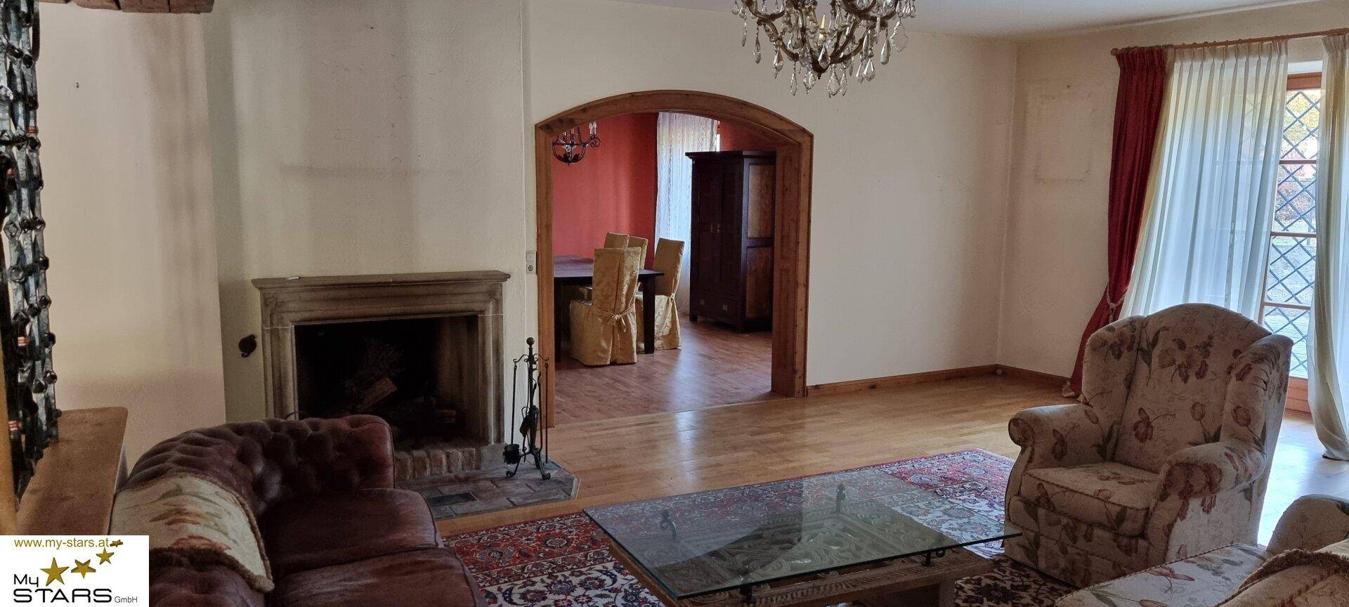 Gemütliches Wohnzimmer mit Kamin, Parkettboden und traditionellen Möbeln.